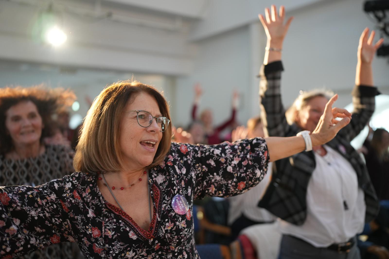 Teilnehmer des Kongresses in Bewegung, Frau mit Brille im Vordergrund